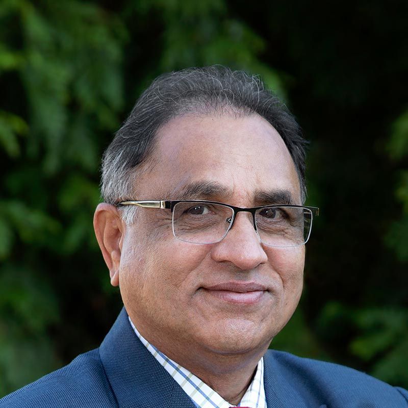 a man wearing glasses and a suit and tie is smiling for the camera .
