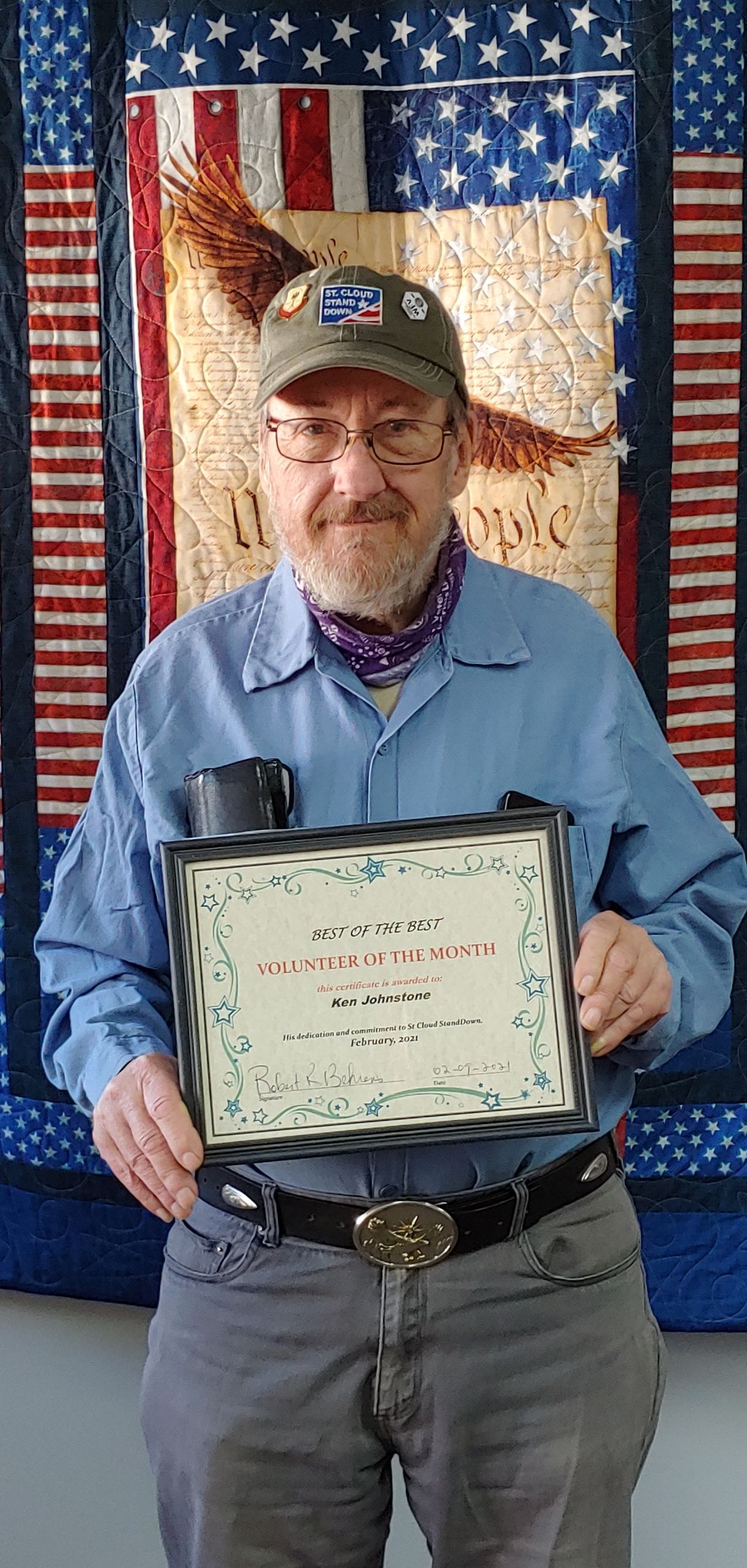 A man is holding a certificate in front of an american flag.
