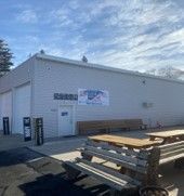 A white building with a picnic table in front of it.