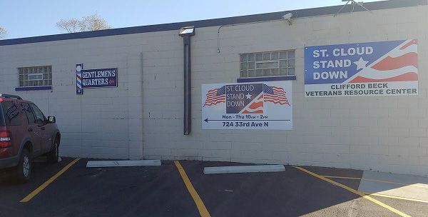 A car is parked in front of a building with a sign that says `` st cloud stand down ''.