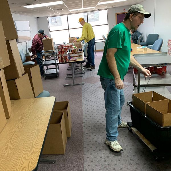 A man in a green shirt is standing in a room full of boxes