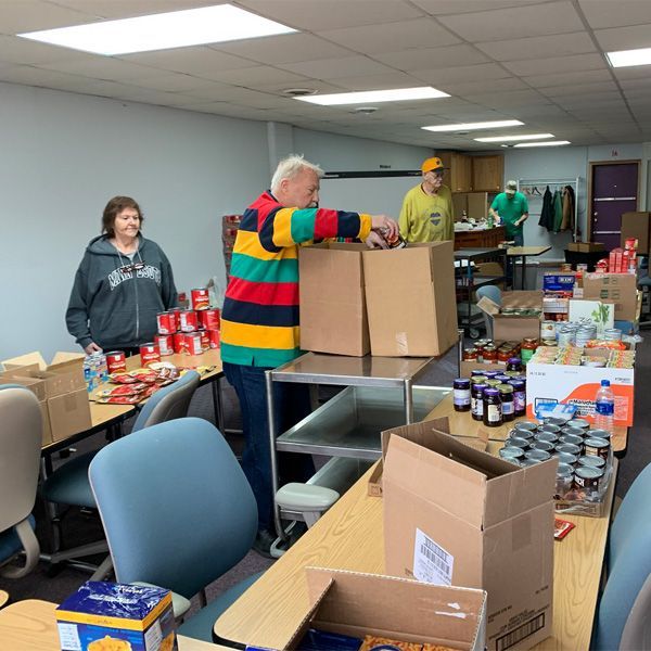 A man in a striped shirt is putting boxes on a table