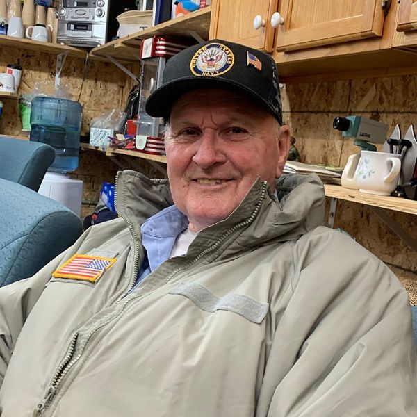 A man wearing a hat and a jacket is smiling for the camera