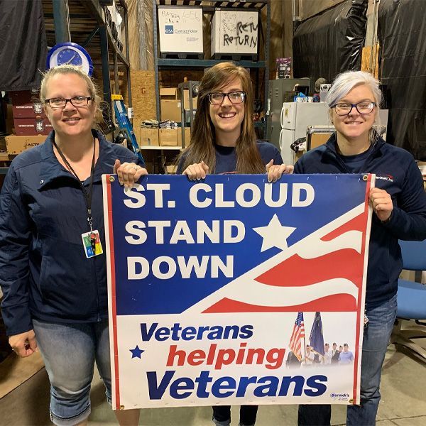 Three women holding a sign that says veterans helping veterans