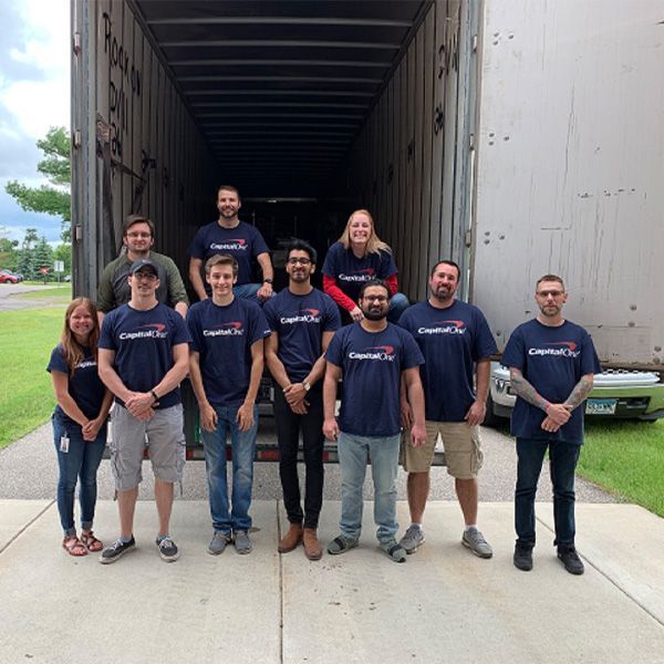 A group of people wearing capital one shirts are standing in front of a truck