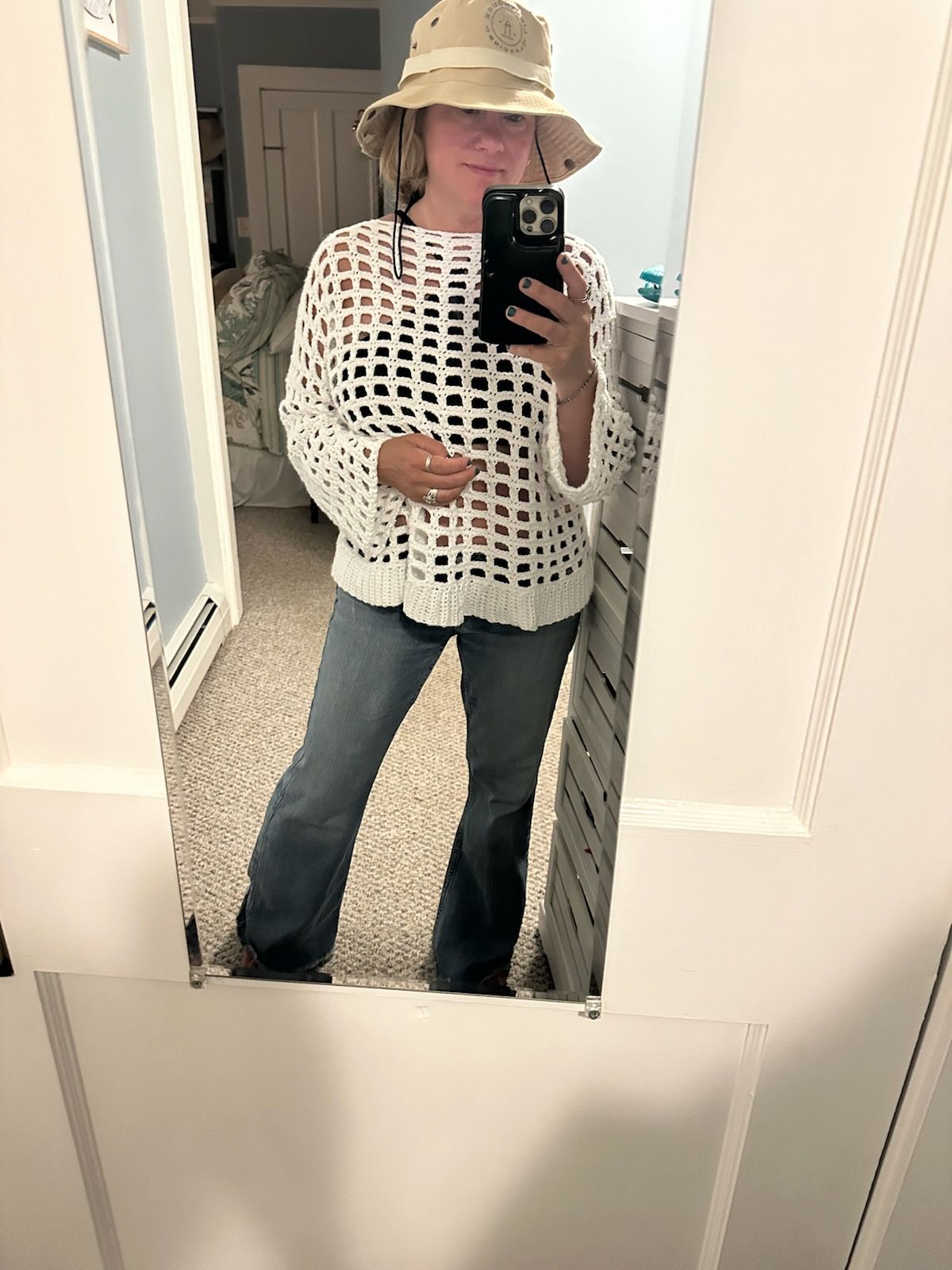 A woman is taking a selfie in front of a mirror while wearing a hat.