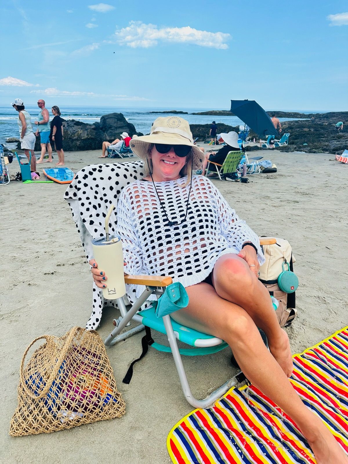 A woman is sitting in a beach chair holding a drink.