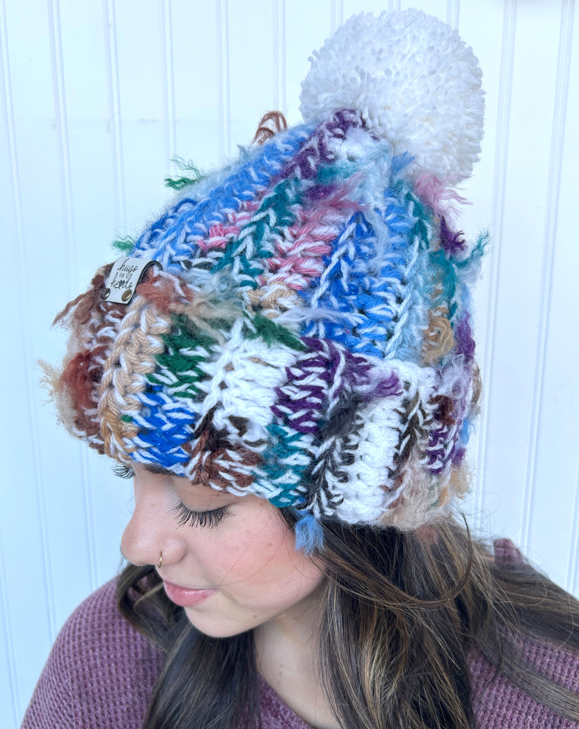 A woman wearing a colorful knitted hat with a pom pom.
