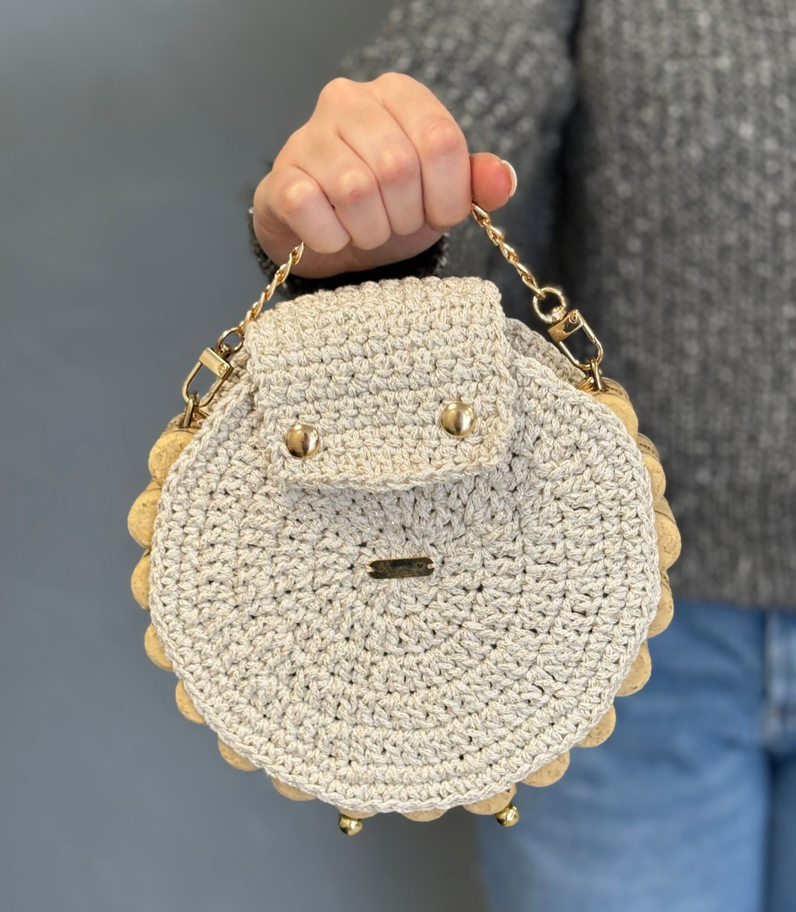 Two people embrace, one with a head covering, eyes closed, and smiling. Gray and pink clothing. Indoors.