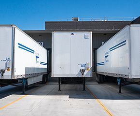 three white semi trucks are parked next to each other in a parking lot .