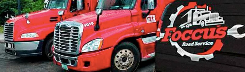 two red trucks are parked next to each other on the side of the road .