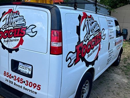 Three batteries in a truck compartment, connected by red and black wires to a battery charger.