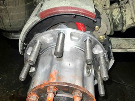 Truck wheel hub assembly with brake components visible, including brake shoes and mounting studs.
