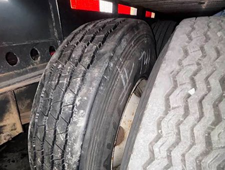 Spare tires stored on a flatbed trailer, visible tire treads and reflective safety markings.