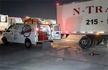 a white van is parked next to a white truck with the number 215 on it .