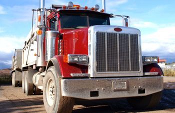 a red semi truck is parked on a dirt road .