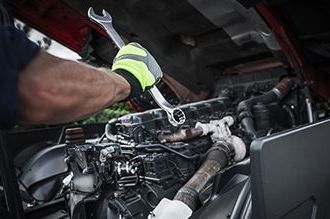 a man is working on a truck engine with a wrench .