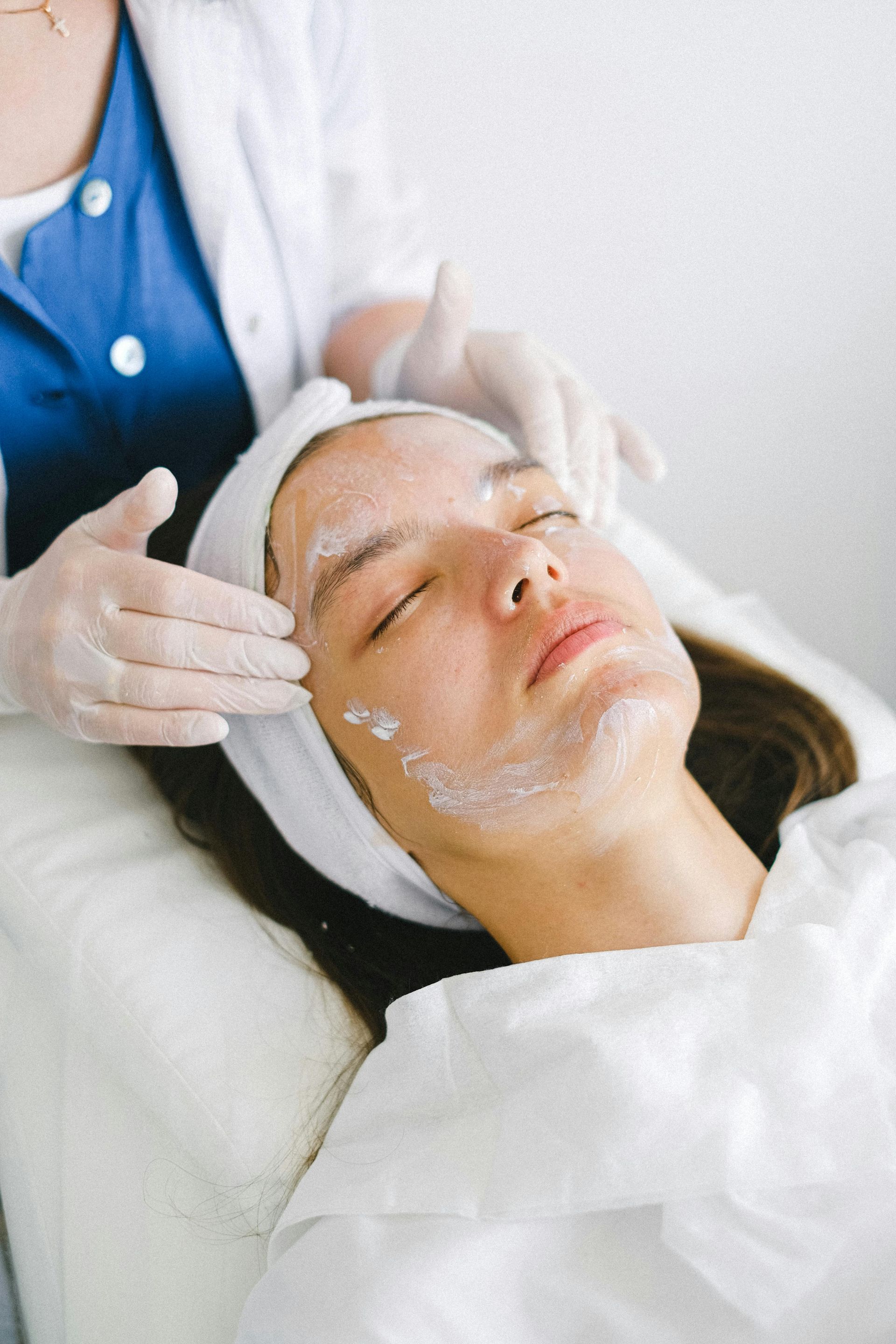 A person in a white headband receives a facial treatment — Pink Lily Beauty in Blacksmiths, NSW