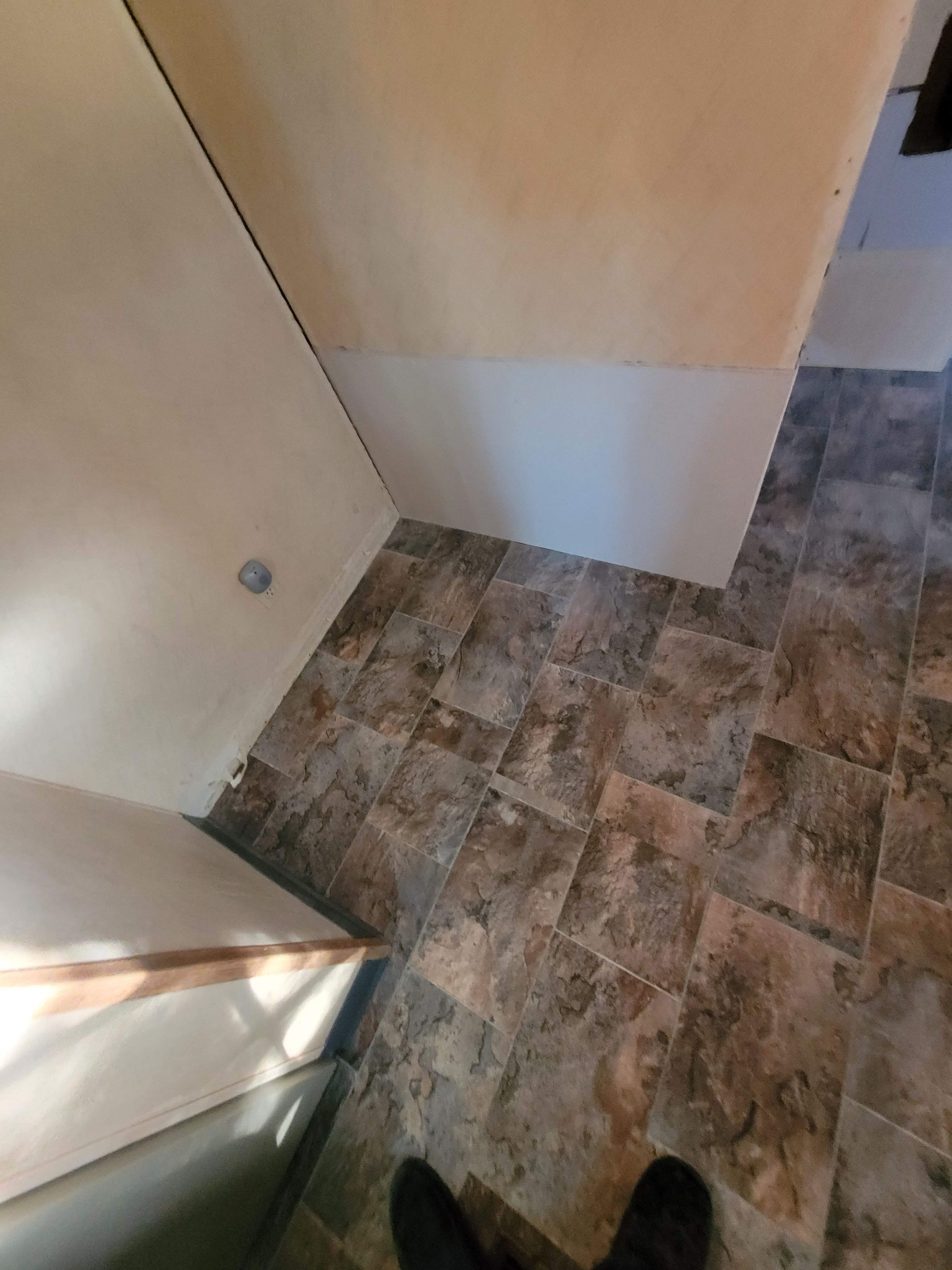 A person is standing on a tiled floor in a room.