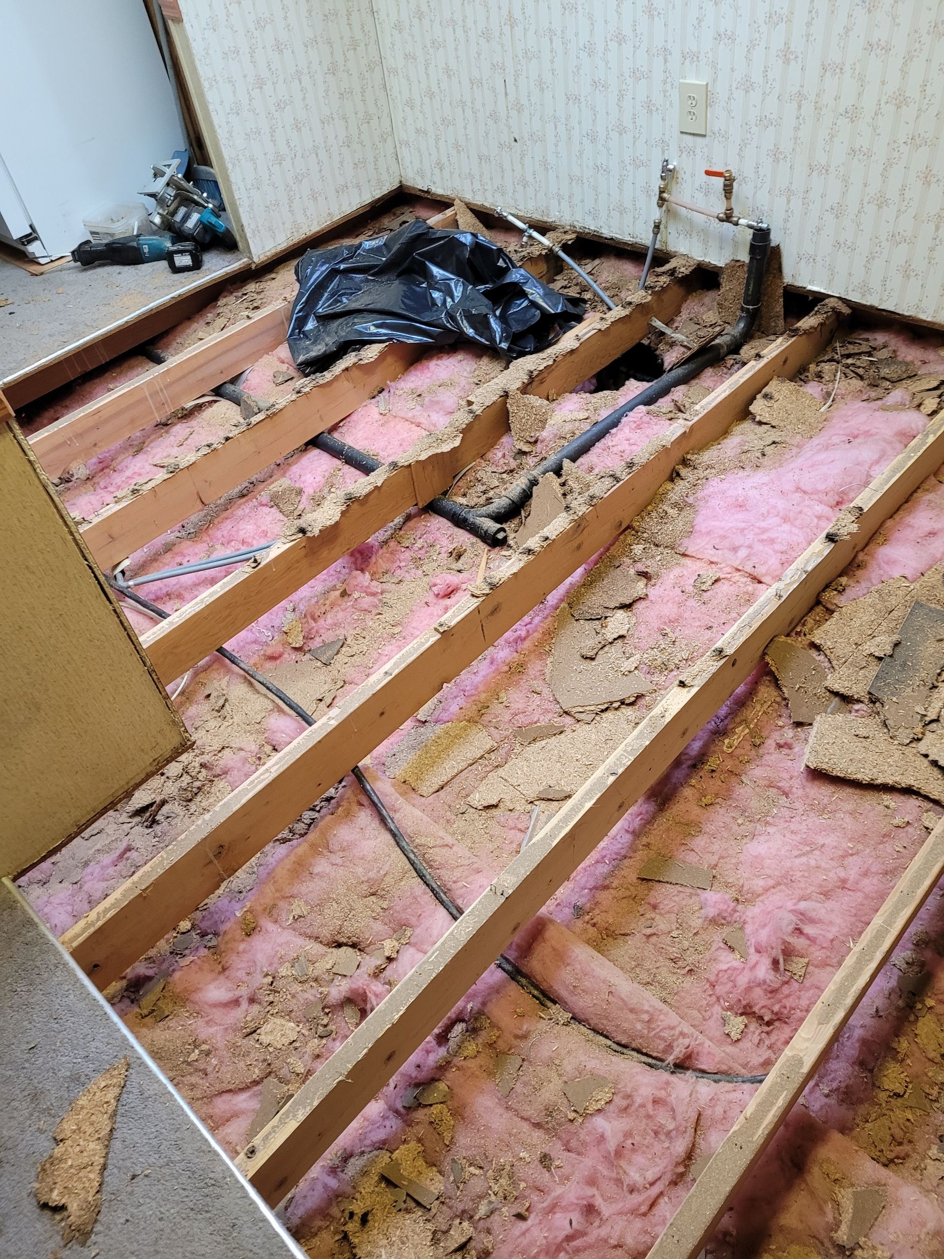 A room with wooden beams and pink insulation on the floor