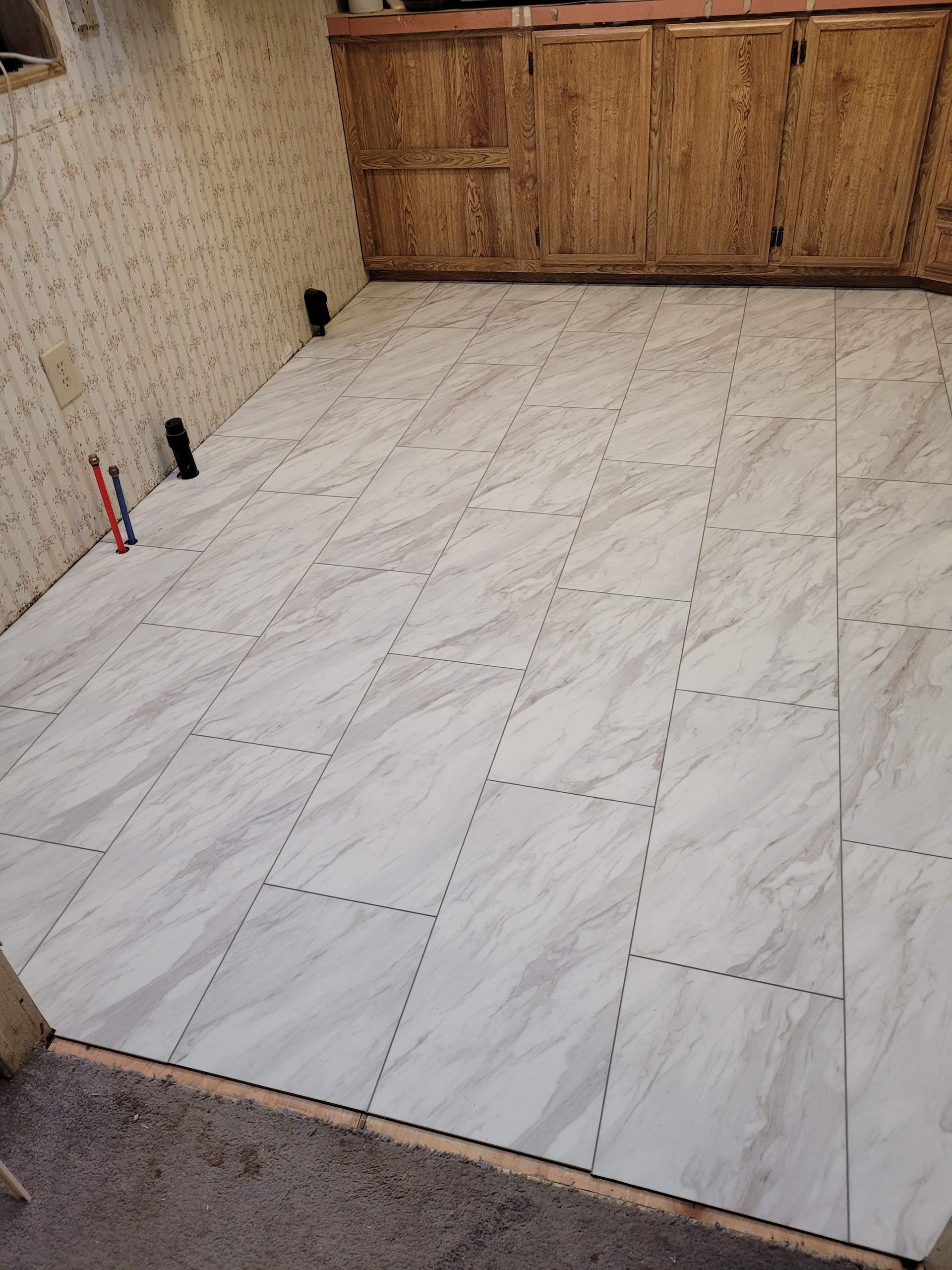 A room with a white tile floor and wooden cabinets.