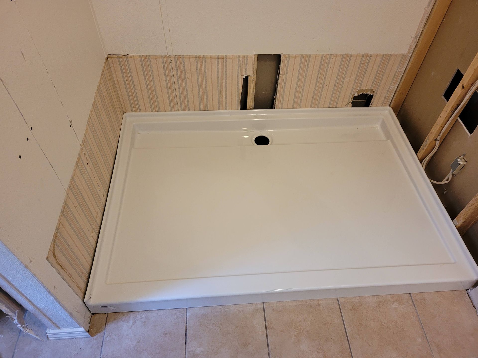 A white shower tray is sitting in a bathroom next to a wall.