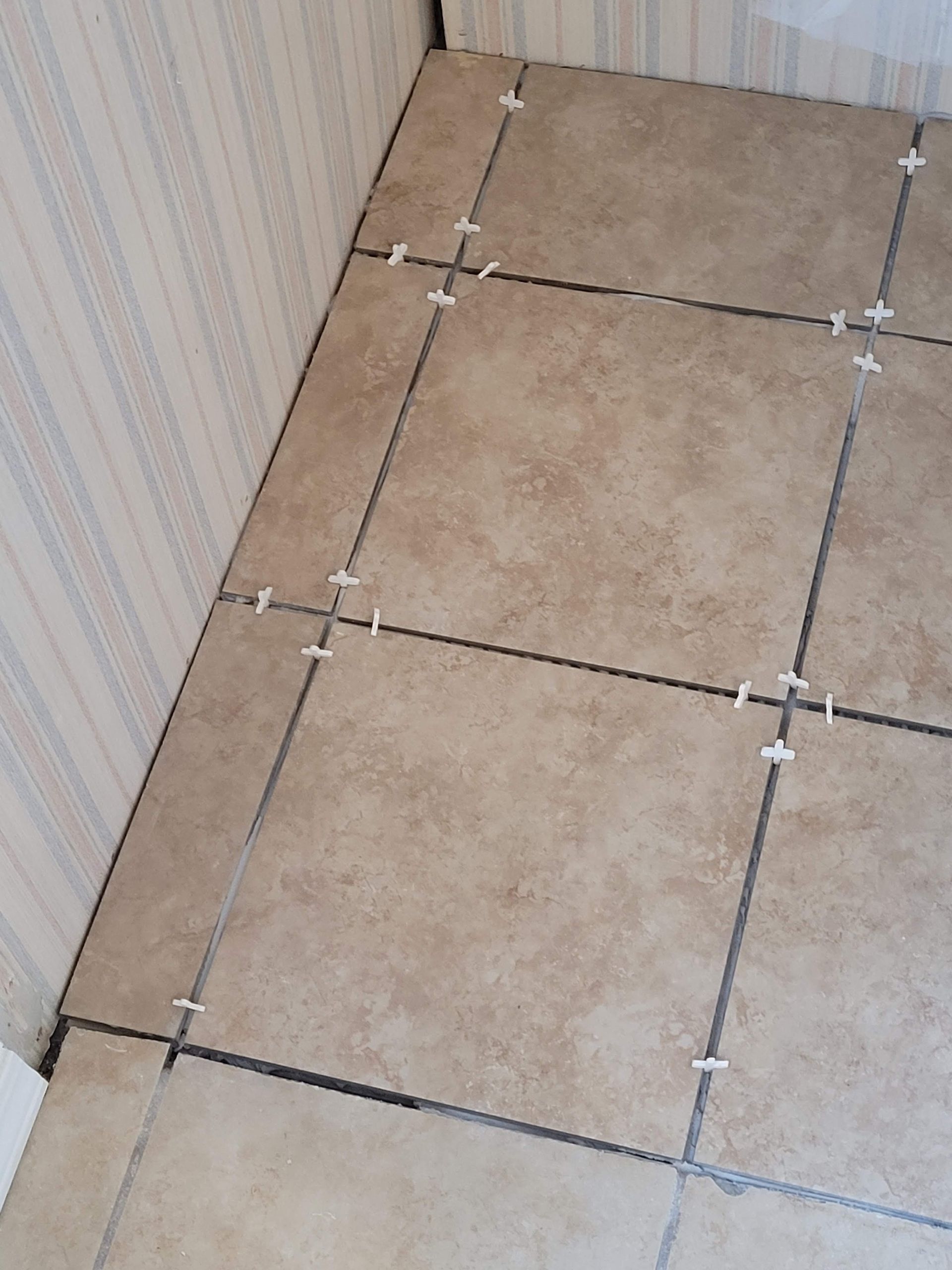 A close up of a tiled floor with spacers on it