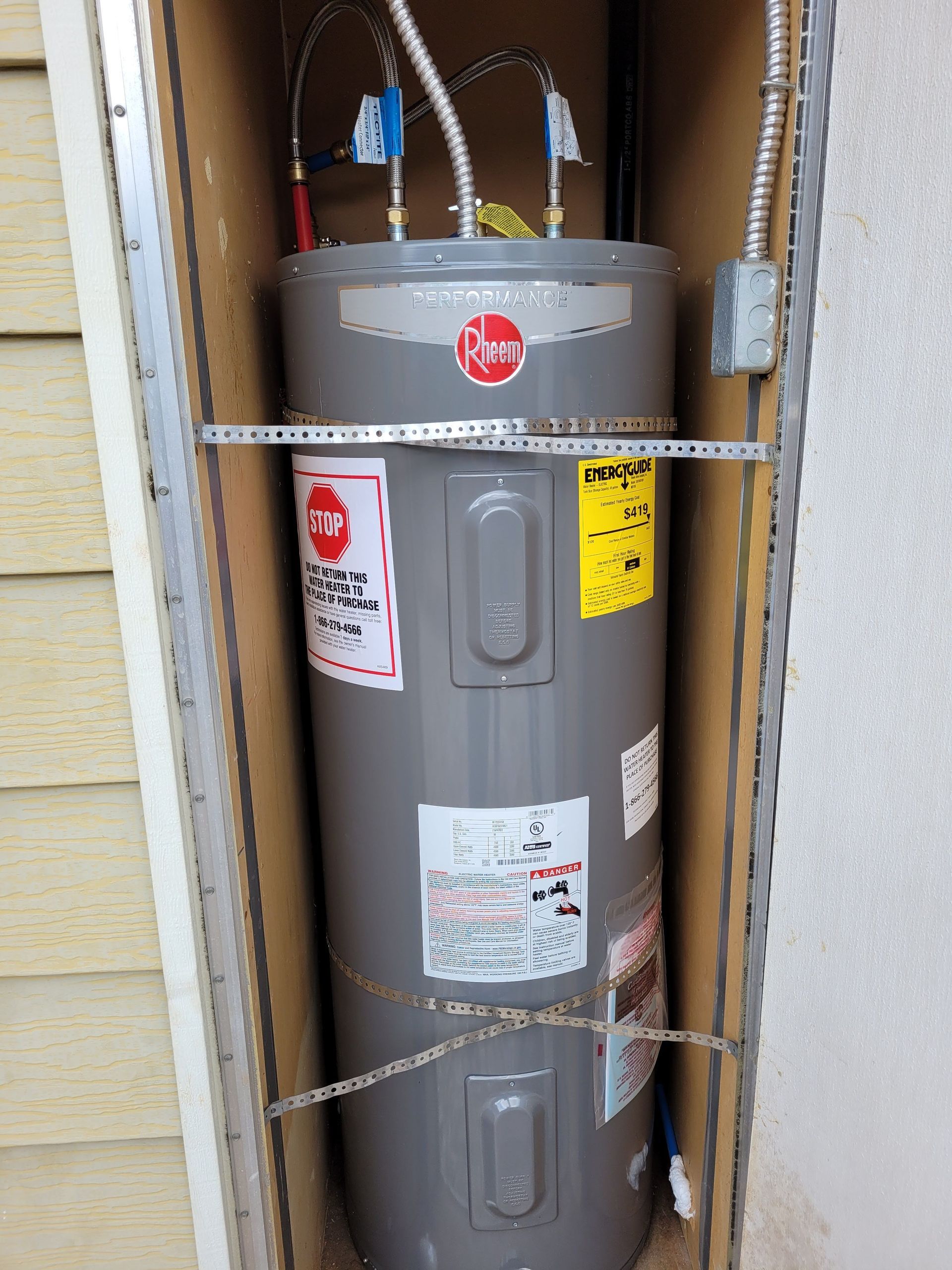 A gray water heater is sitting inside of a cardboard box.