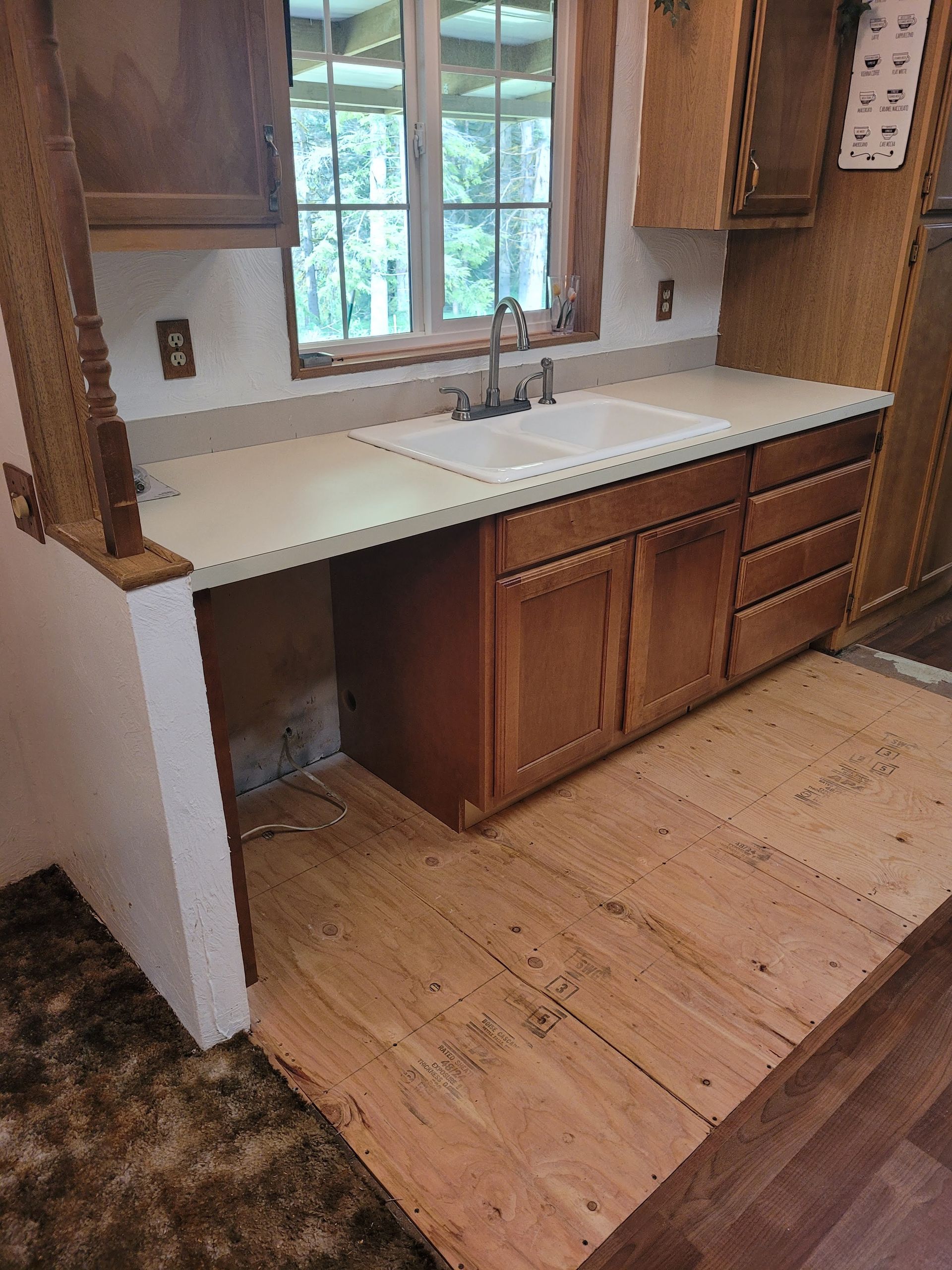 A kitchen with wooden cabinets , a sink , and a window.