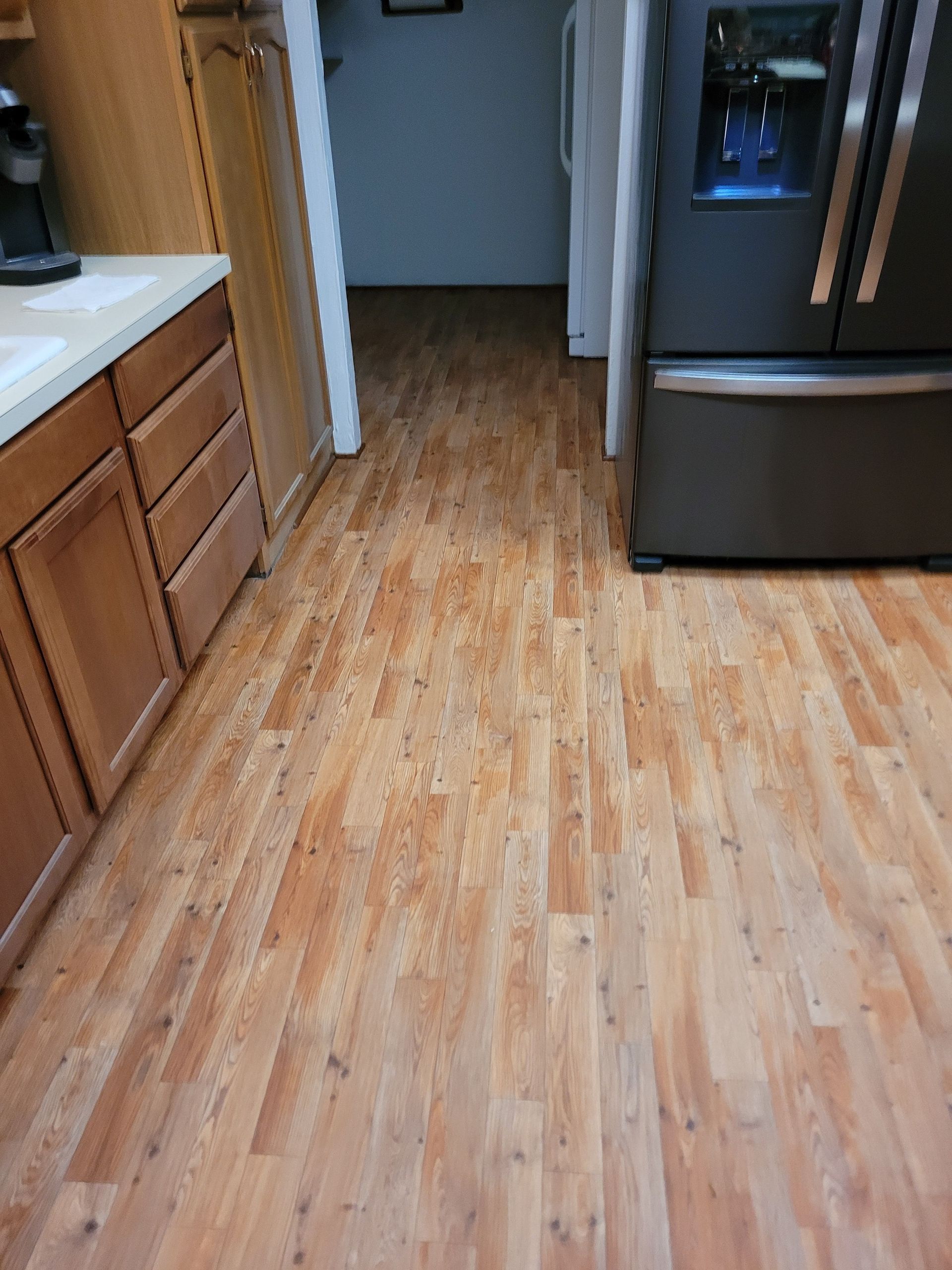 A kitchen with hardwood floors and a refrigerator.