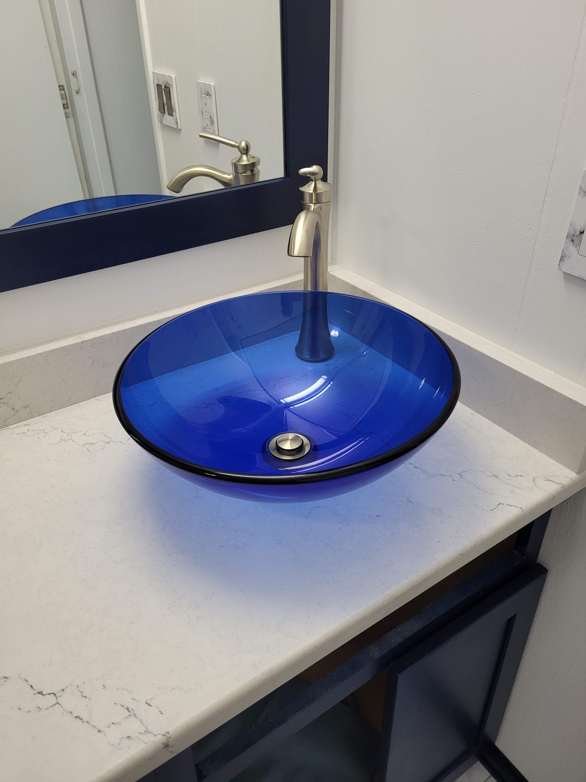 A blue sink is sitting on top of a white counter in a bathroom.