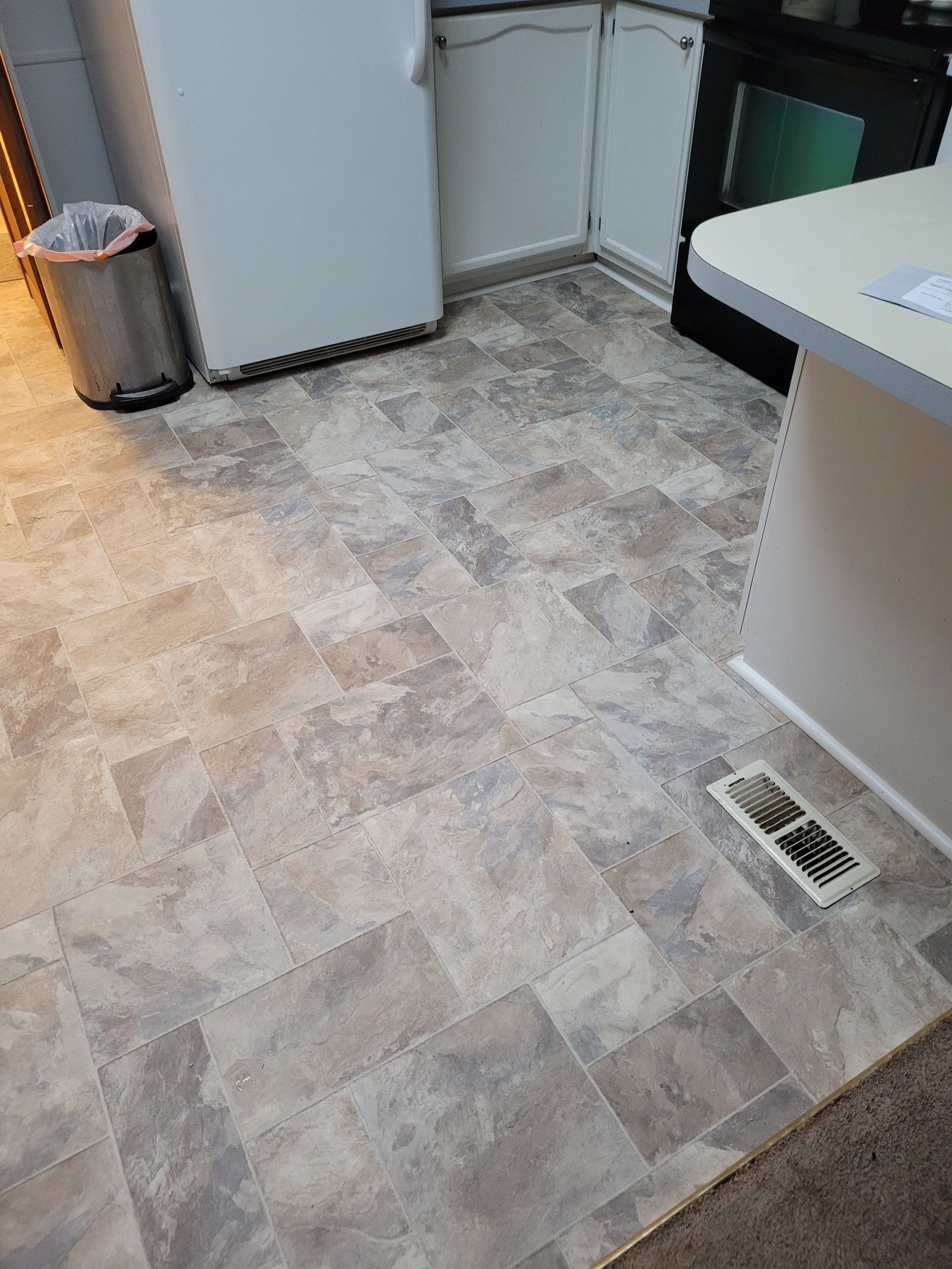 A kitchen with a tile floor and a refrigerator.