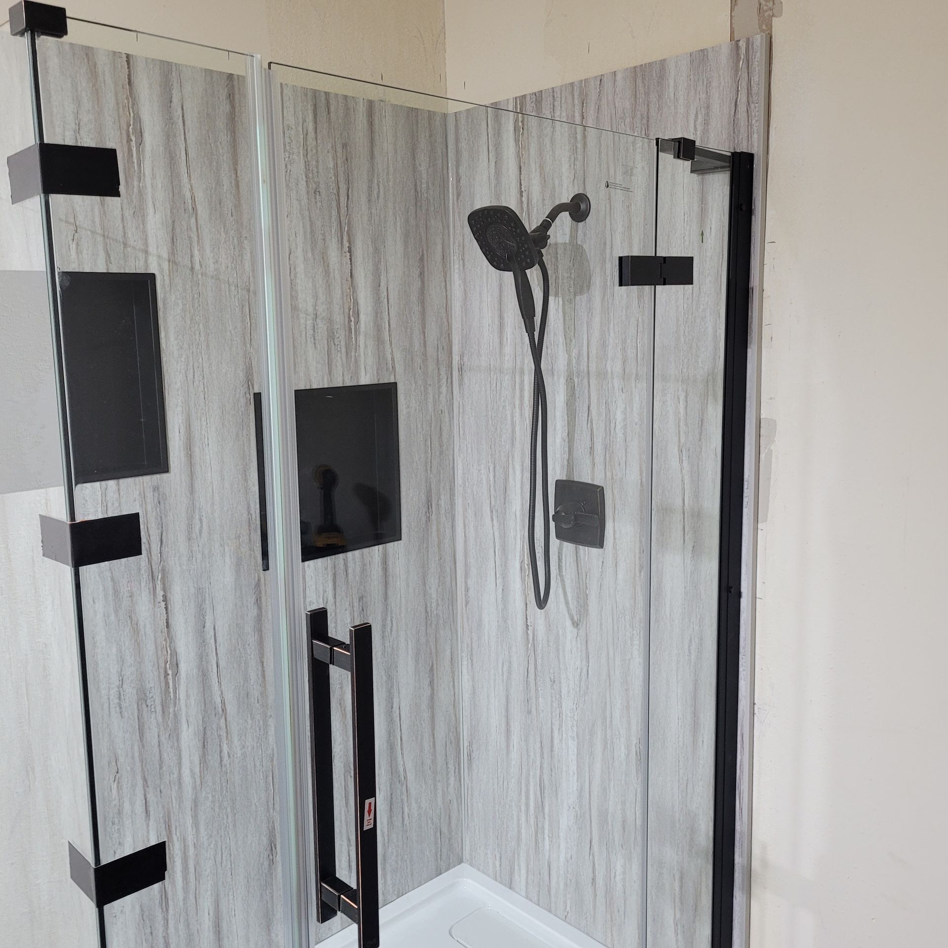 A shower stall with a black handle and a shower head