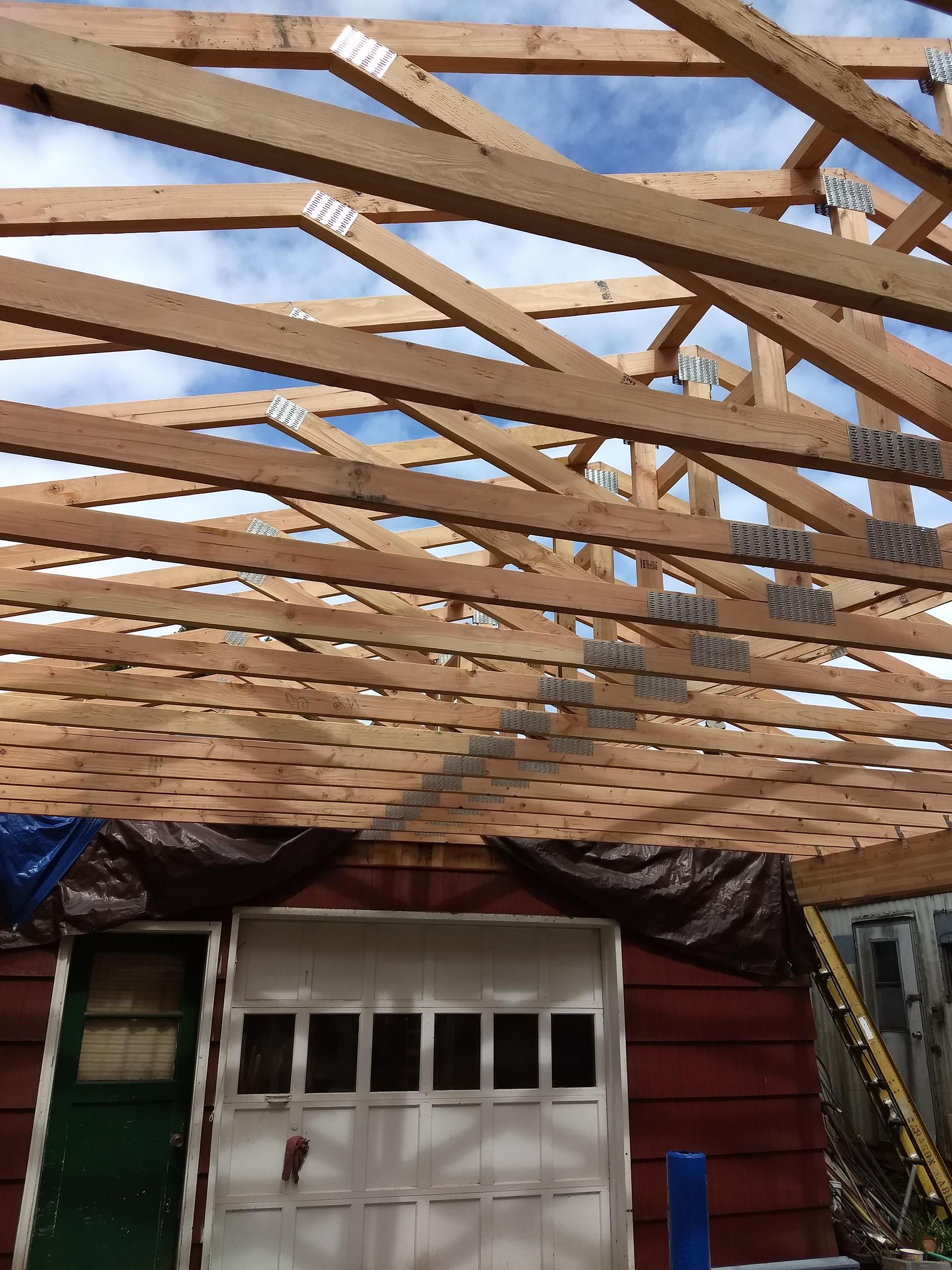 The roof of a garage is being built with wooden beams