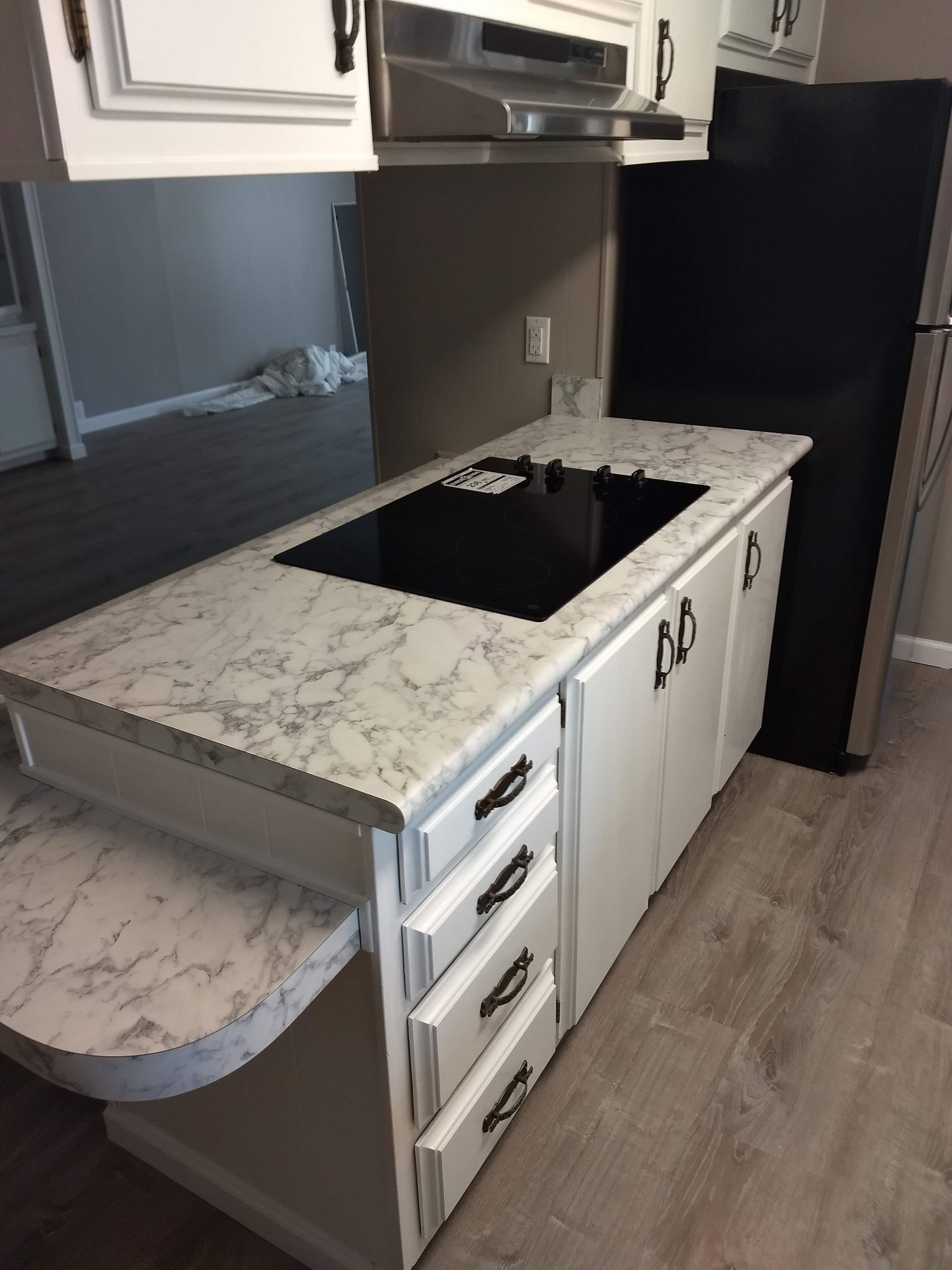 A kitchen with white cabinets and a black refrigerator