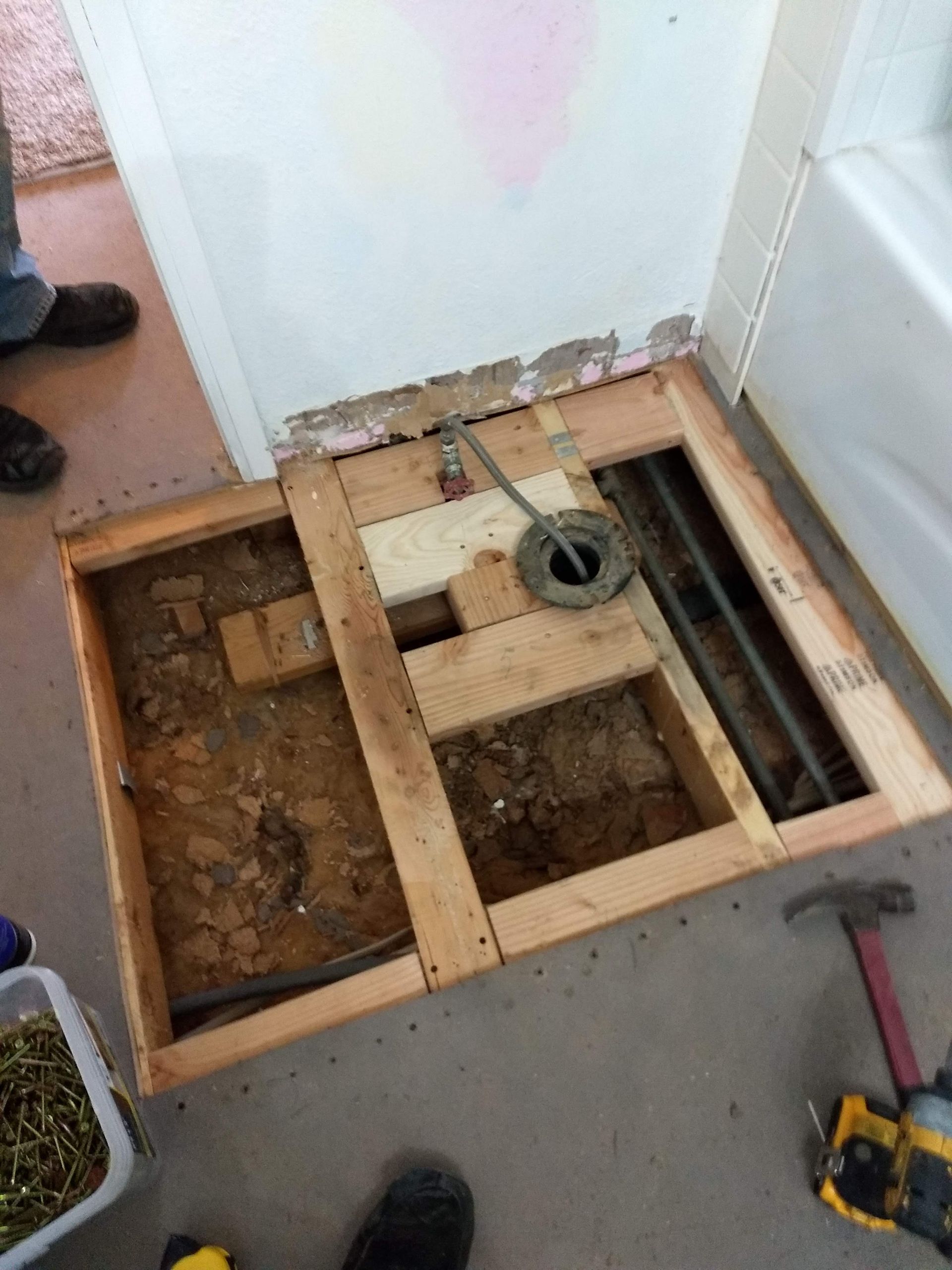 A person is working on a wooden floor in a bathroom