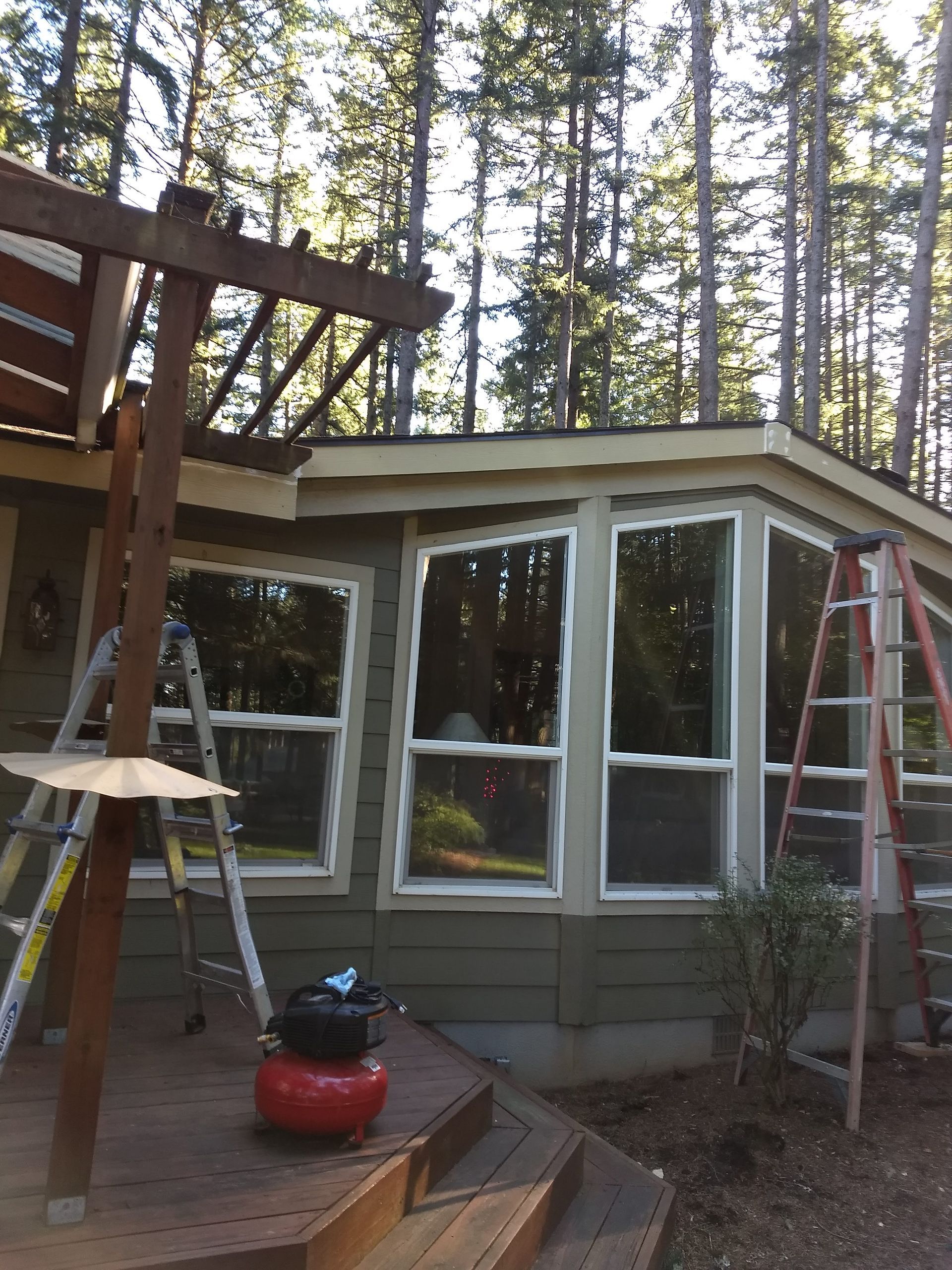 A house with a lot of windows and a ladder in front of it