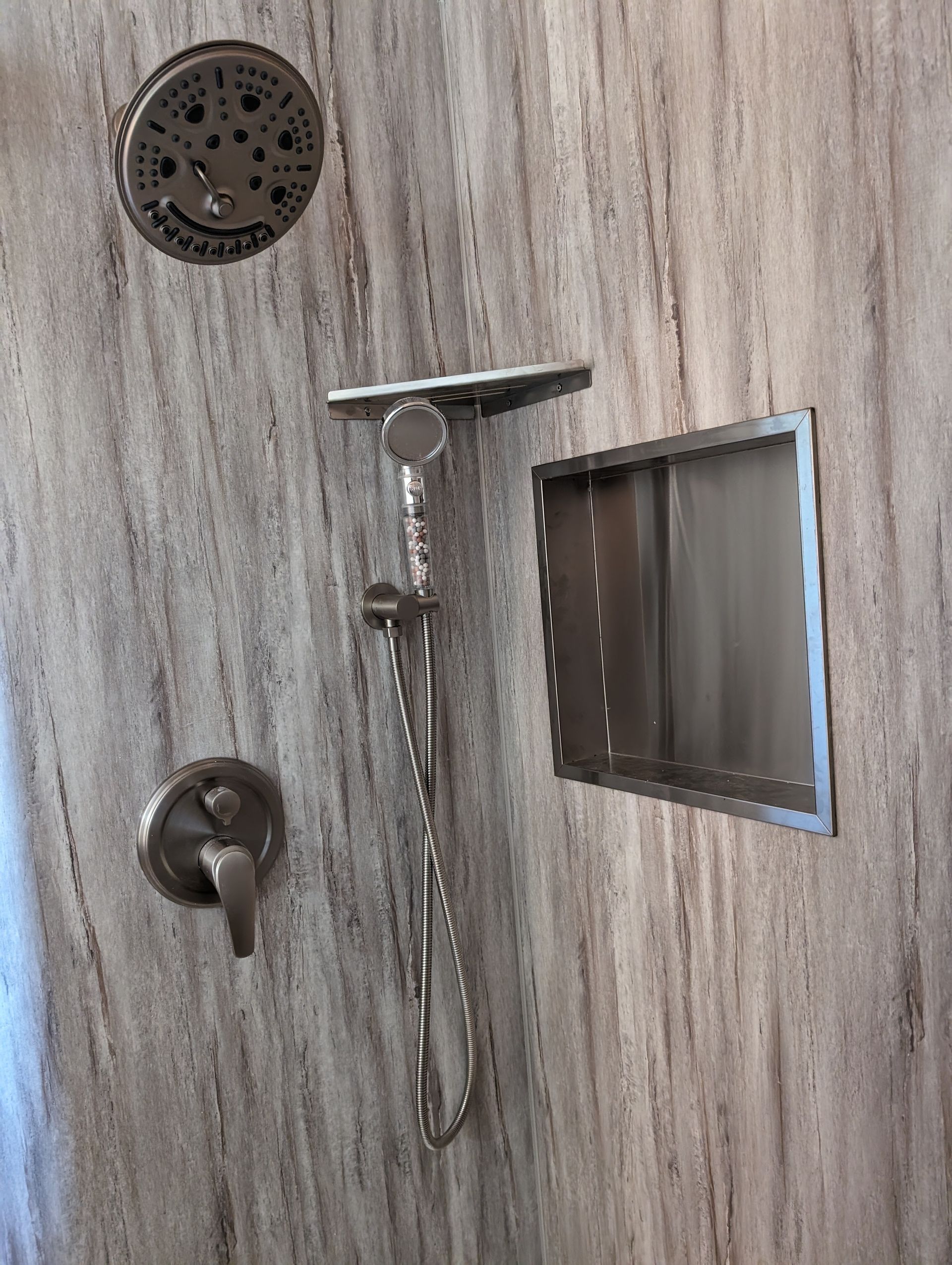 There is a shower head and a soap dish in the shower.