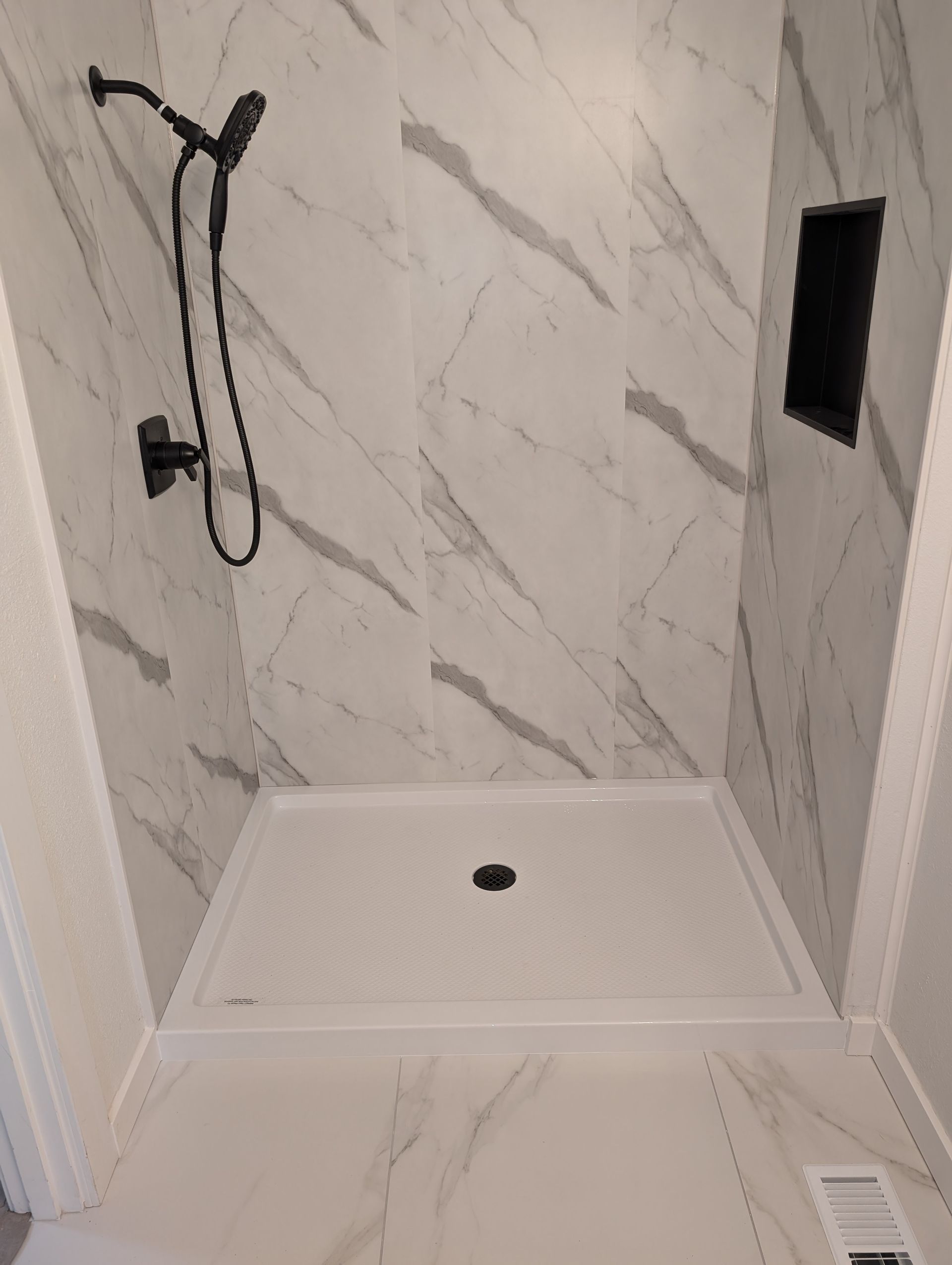 A shower stall with marble walls and a shower head.