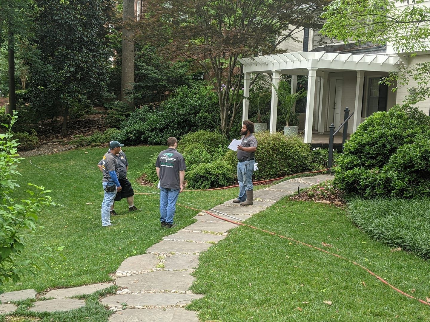 A group of men are standing on a sidewalk in front of a house.