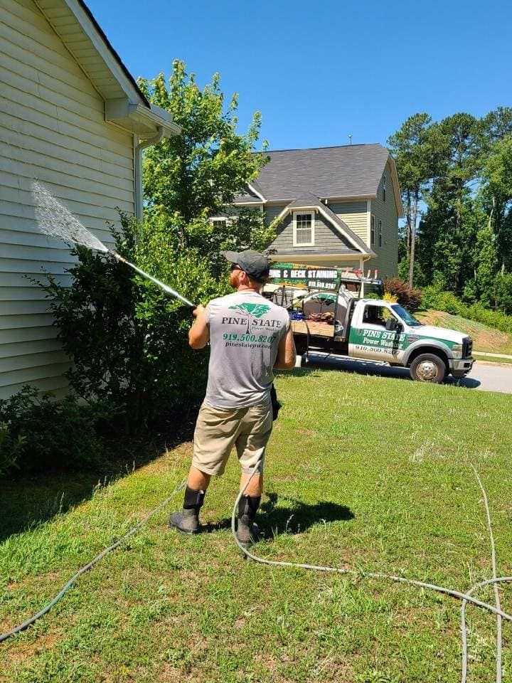 A man is washing the side of a house with a hose.