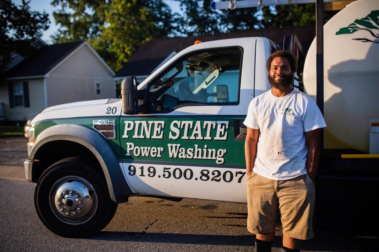 A man is standing in front of a pine state power washing truck