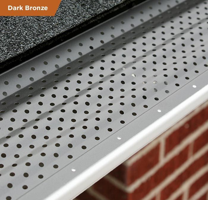 A close up of a dark bronze gutter guard on a brick wall