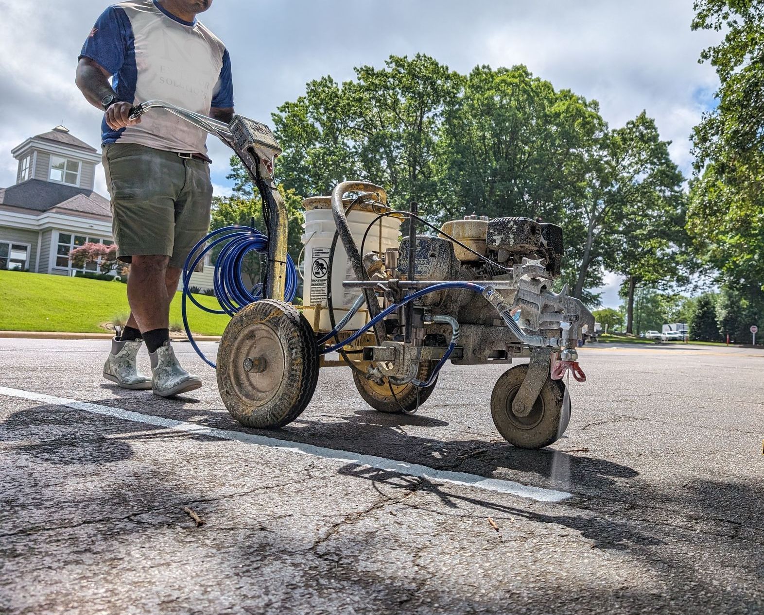 A man is painting a line on the road with a machine.