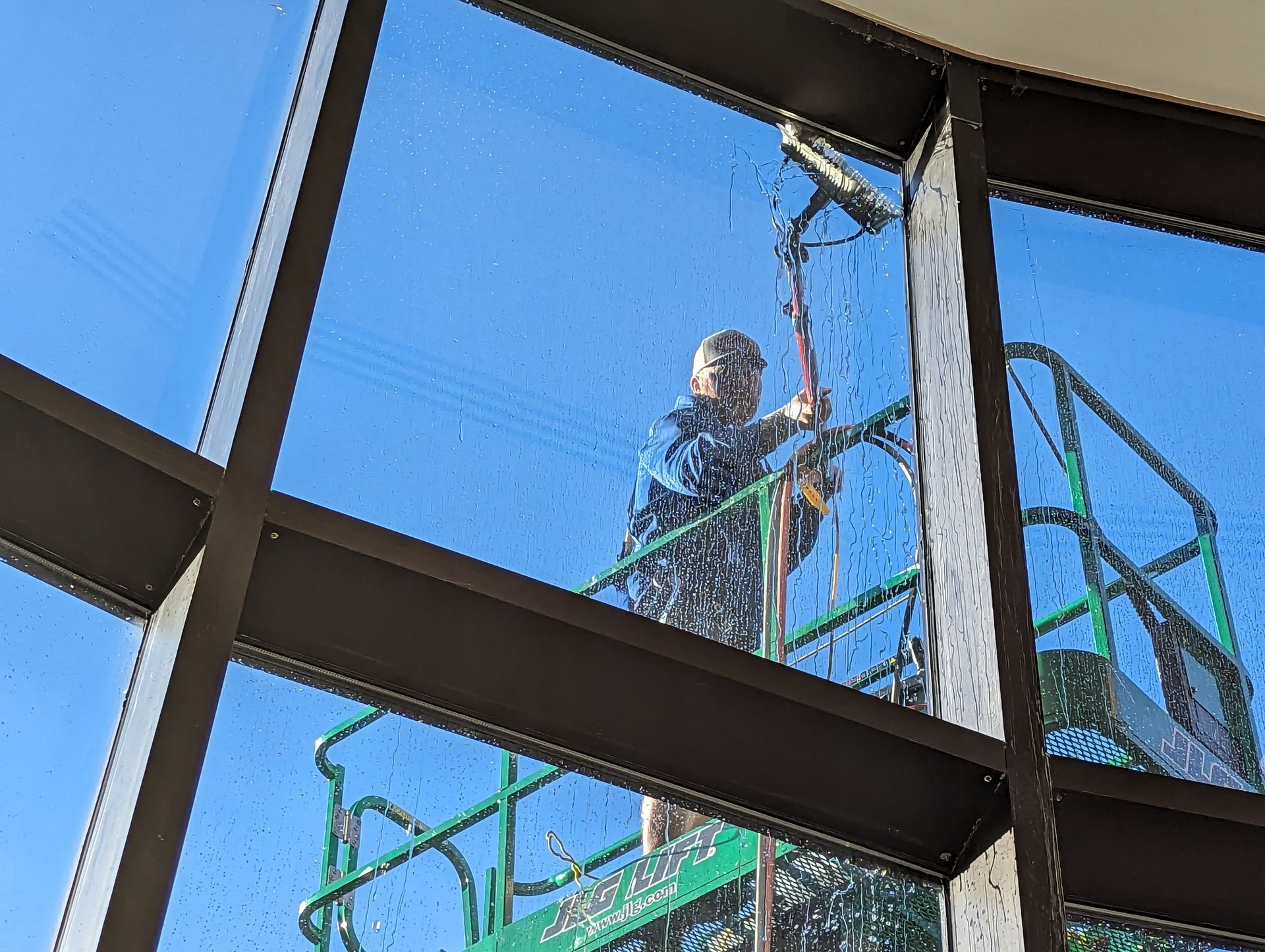 A man is cleaning a window on a scaffolding.