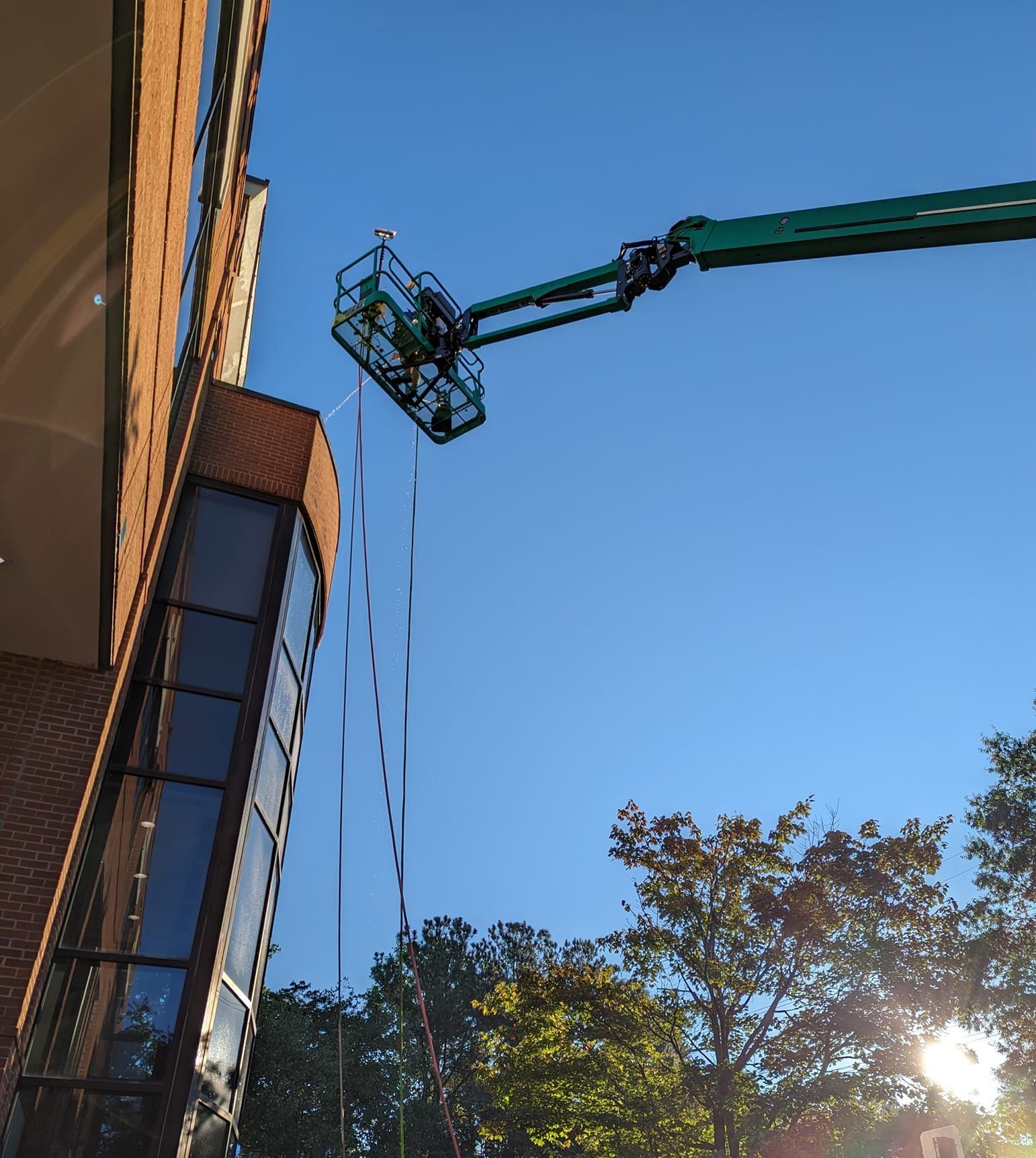 A green crane is hanging from the side of a building