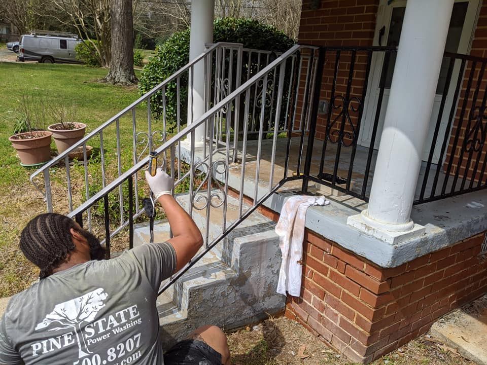 A close-up of a Pine State Pro Wash worker applying enamel to a wrought iron railing in Raleigh, NC