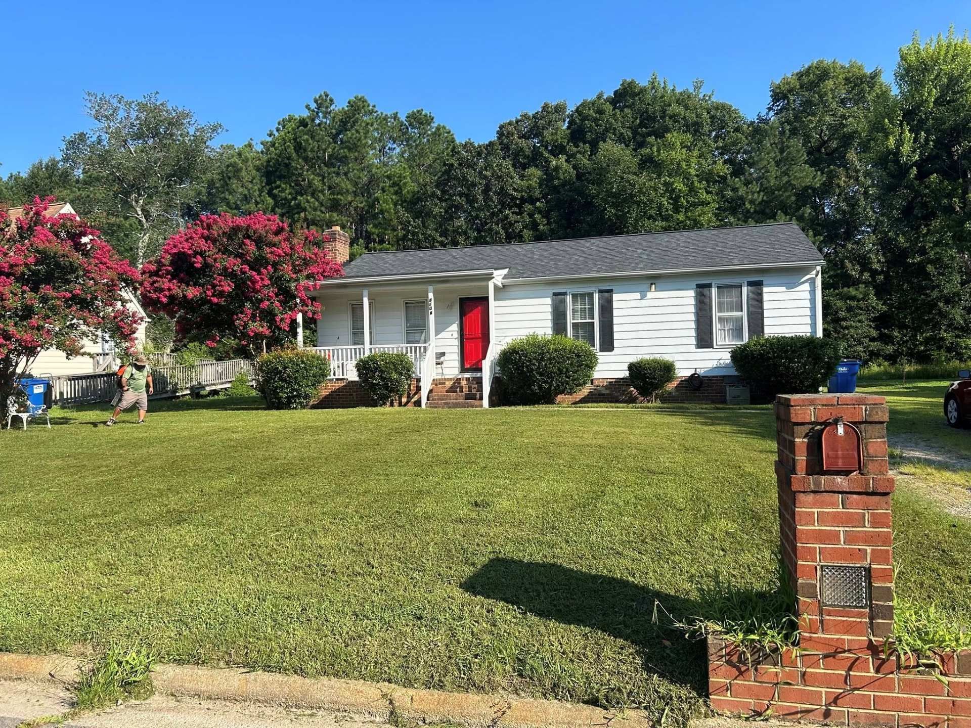 White house with red door, black shutters, and brick mailbox in front yard.