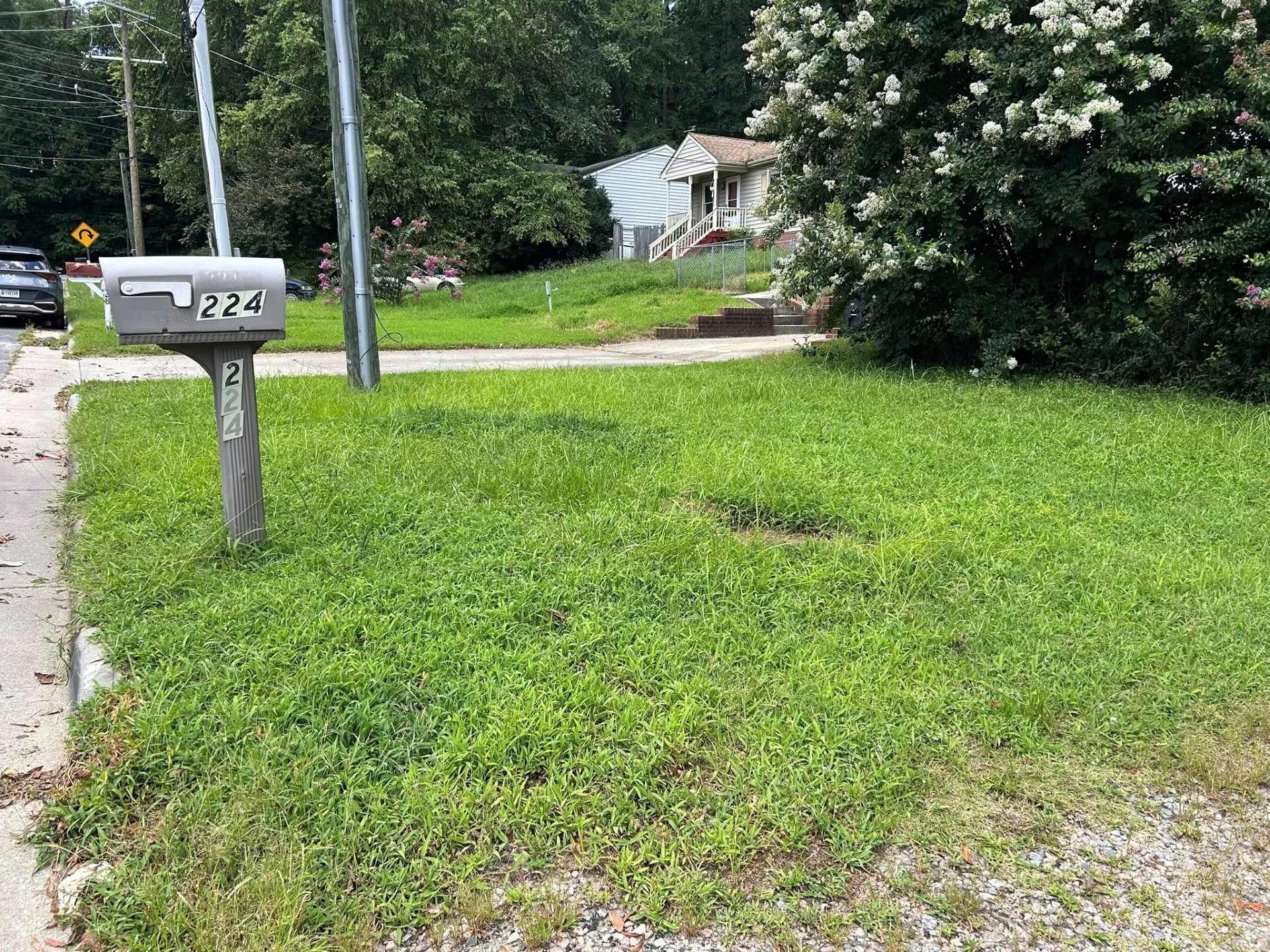 A mailbox (222) next to a grassy lawn; a house sits behind a hill.