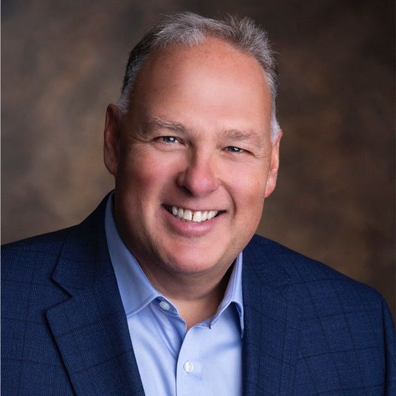 A man and a woman are sitting on a dock overlooking a lake.